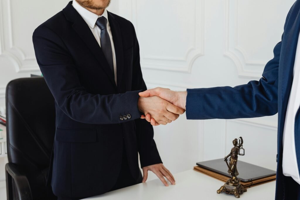 pexels photo 7875996 7875996 Two men in suits shaking hands in a formal office environment symbolizing an agreement.